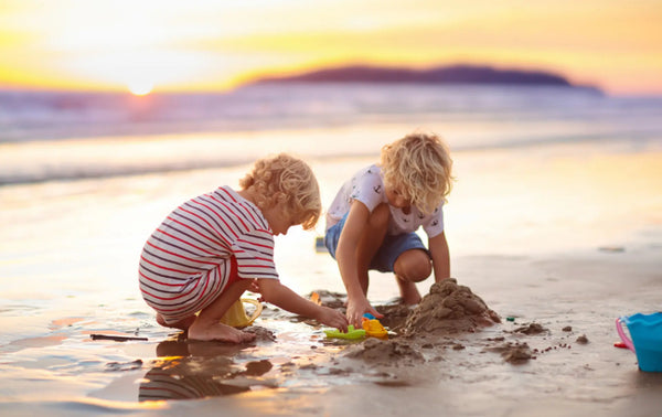 To barn leker i sanden på Bali strand med spade famileferie